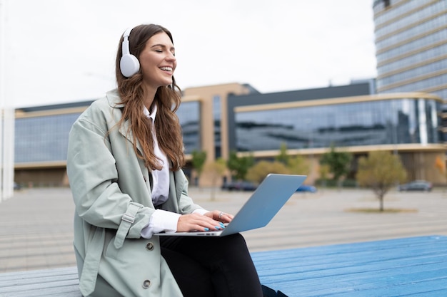 Woman freelancer in headphones working on a laptop against the backdrop of the office