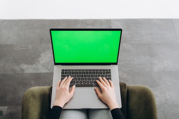 Woman freelancer using laptop computer with a green screen on monitor Concept remote work