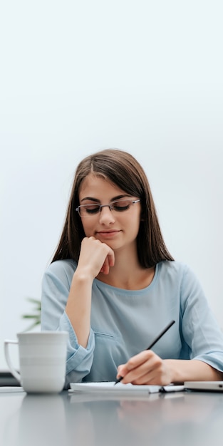 Woman freelancer with pen writing on notebook at home or office.