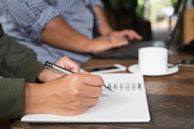 Woman freelancer working hand writing journal on small notebook