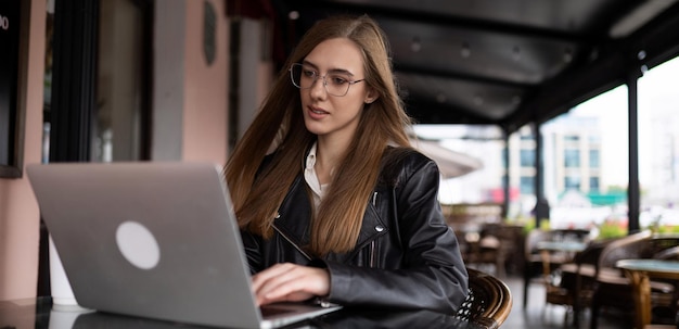 Woman freelancer working online on laptop in city cafe