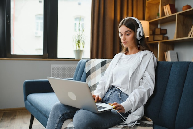 自宅のソファでラップトップを操作する女性フリーランサー ワーキングガールのポートレート