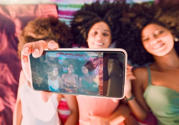 Foto amici della donna e telefono per selfie di gruppo estate e relax per l'amicizia in viaggio o in vacanza insieme donne felici che si rilassano sdraiate sugli asciugamani da spiaggia sorridendo per foto tenendo smartphone con display