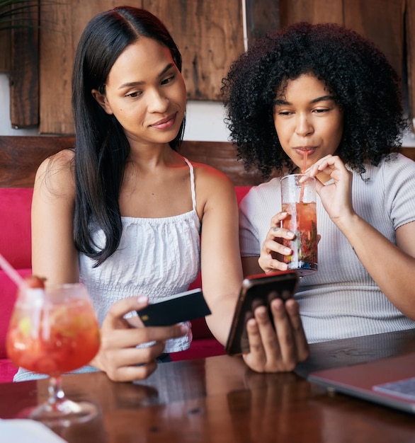 Женщины-друзья и телефон с кредитной картой пьют в баре ресторана или кафе, совершая онлайн-платеж или транзакцию Женщины отдыхают вместе, выпивая в электронной коммерции или дистанционном банкинге на смартфоне