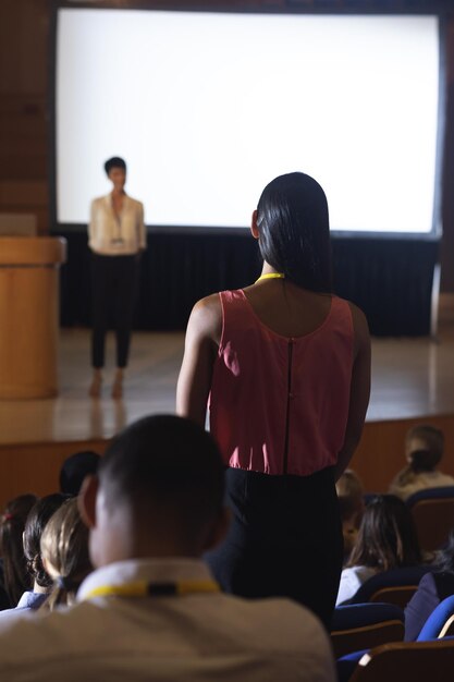 Foto donna del pubblico in piedi e chiedendo una domanda nell'auditorium