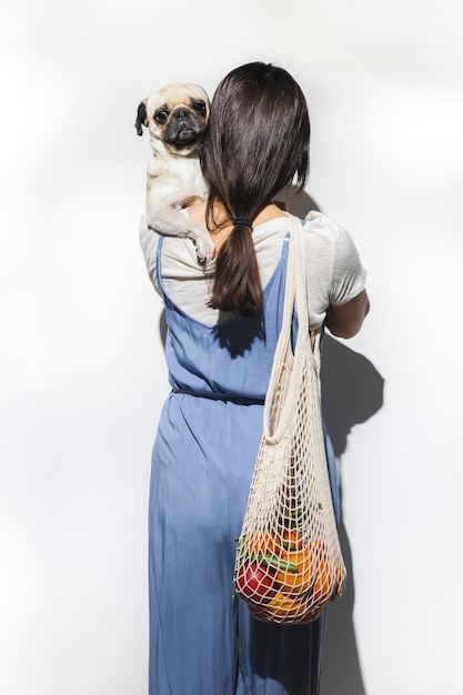 Woman from behind with pug dog going to do the shopping Shopping with dog