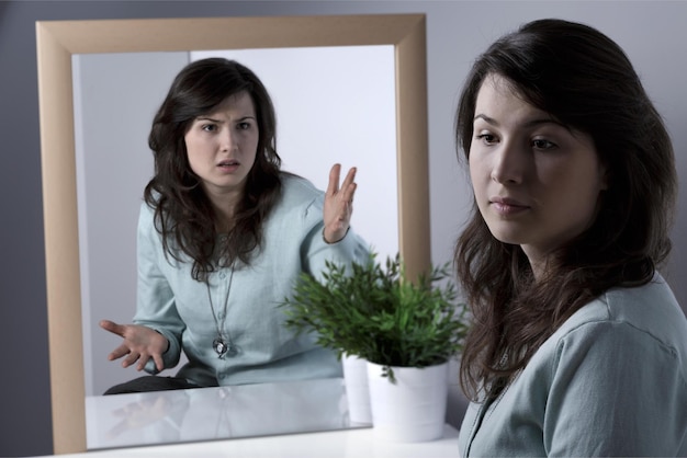 A woman in front of a mirror is looking at her reflection.