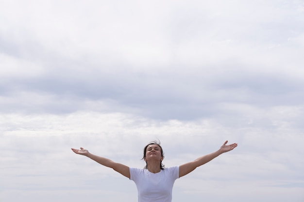 Woman in front with white shirt raising her arms to the sky