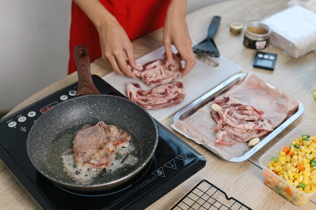 Photo woman frying beef meat on pan in the kitchen