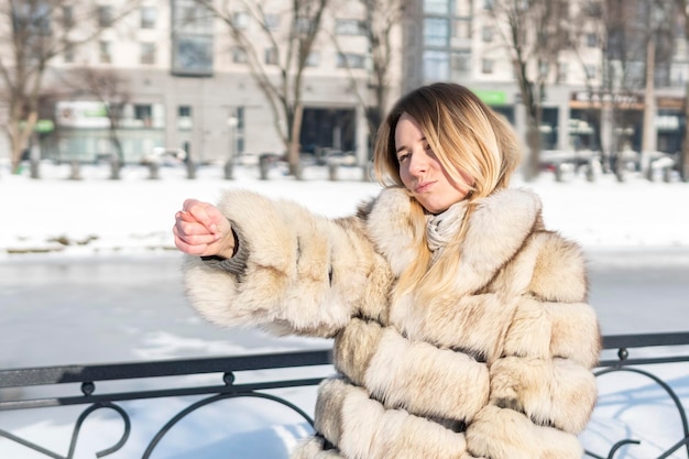 Photo woman in a fur coat shows a fig away from the camera