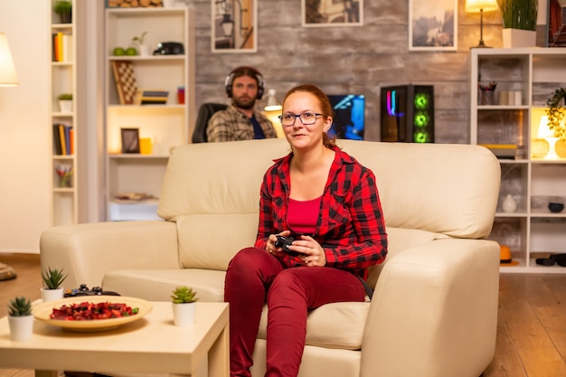 Woman gamer playing video games on the console in the living room late at night