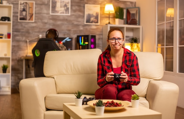 Woman gamer playing video games on the console in the living room late at night