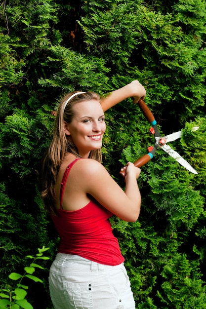 Woman in garden trimming hedge