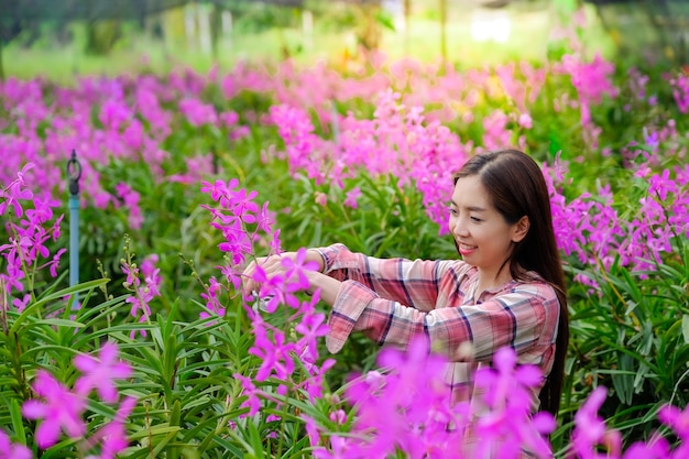 Foto una donna giardiniera taglia le orchidee viola nel giardino in vendita al mattino