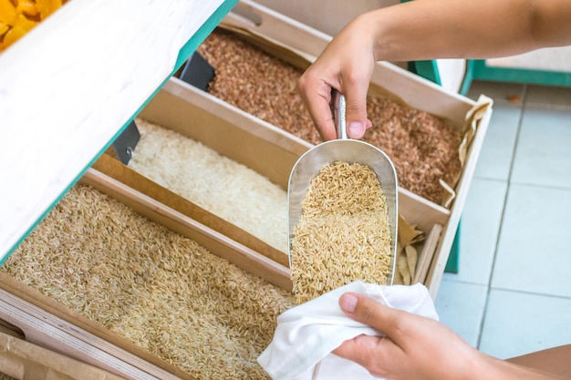 woman gathers cereals in a reusable cotton swab in a store without packaging