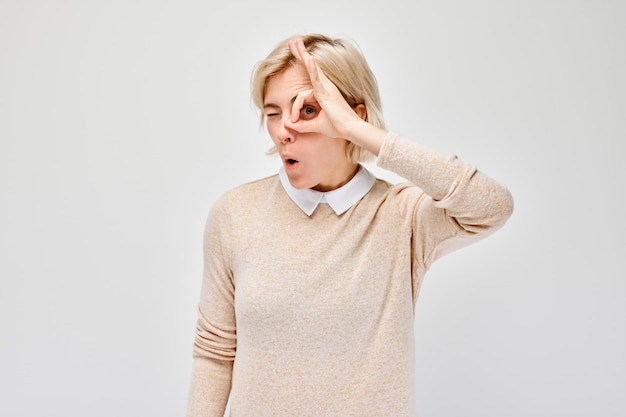 Woman gesturing Ive got my eye on you against a plain background