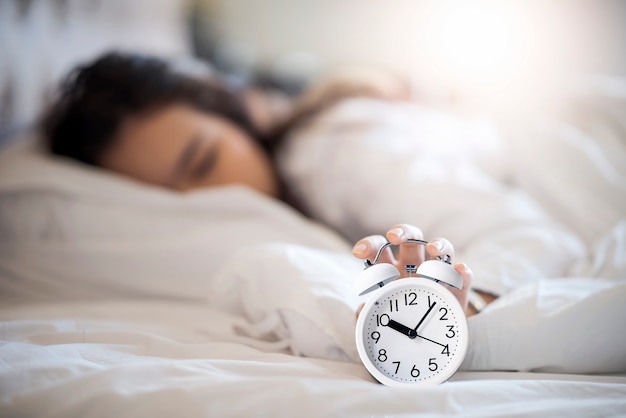 Woman get up late in the morning and try to turning off the alarm clock.