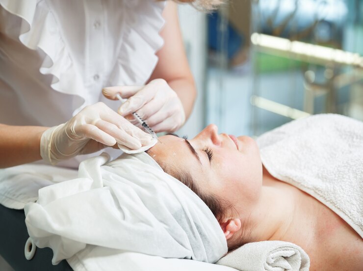 Woman gets cosmetic injection in forehead. Hyaluronic acid injection