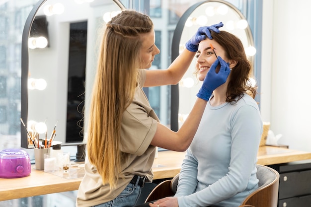 Женщина получает лечение бровей от косметолога