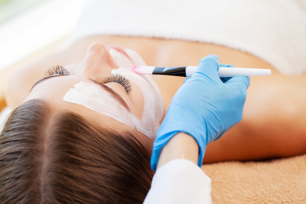 Woman getting facial care by beautician at spa salon