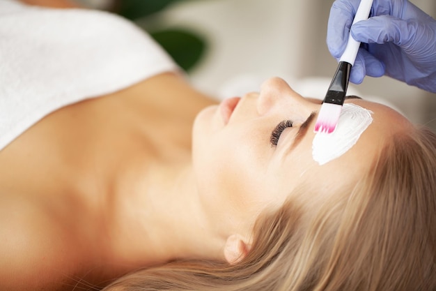 Woman getting facial care by beautician at spa salon