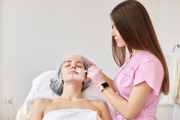 Woman getting facial care by beautician at spa salon.