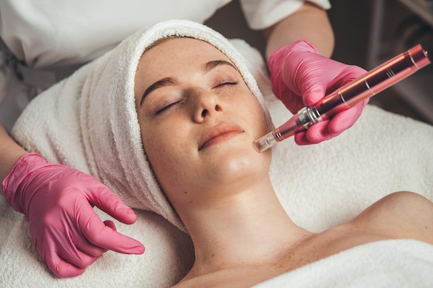 Woman getting facial treatment of chin zone with derma pen at spa salon Skin treatment Medicine medical health Beauty skin Woman beauty face