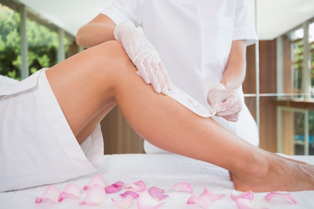 Woman getting her legs waxed by beauty therapist