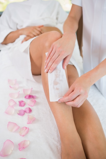 Woman getting her legs waxed by beauty therapist