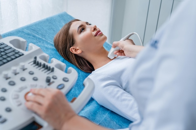 Женщине-врачу осматривает шею женщина-врач с помощью ультразвукового сканера в современной клинике