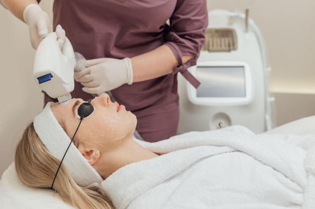 Woman getting laser face treatment in medical spa center