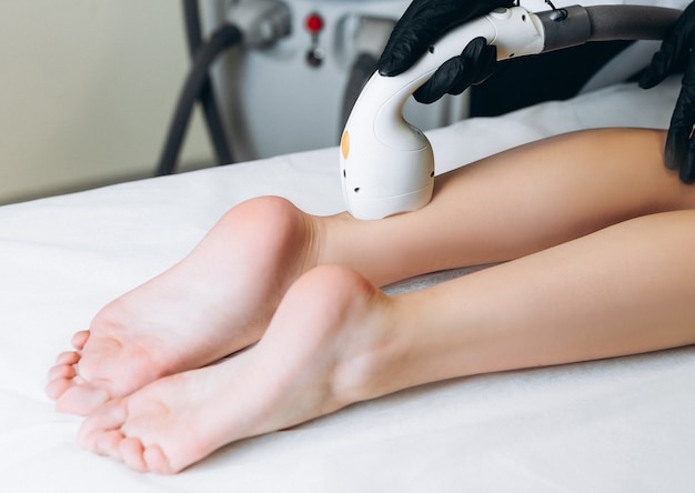 美容院で脚にレーザー治療を受けている女性。