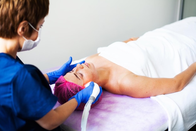 Женщина получает аппаратный массаж LPG в клинике красоты Профессиональный косметолог работает