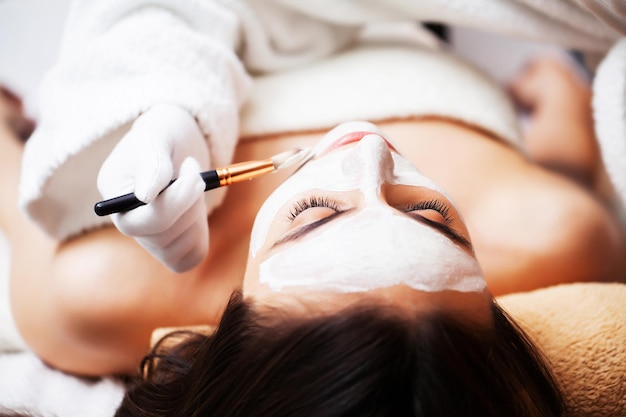 Woman getting spa face mask in beauty studio