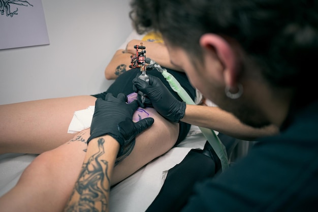 Woman Getting a Tattoo on His Leg