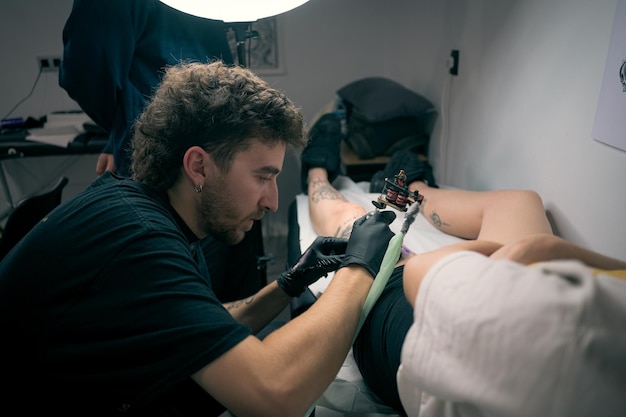 Woman Getting a Tattoo on His Leg