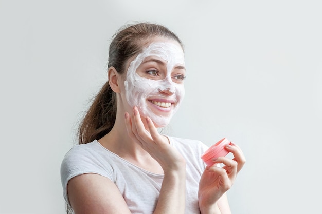 Photo woman girl applying white nourishing mask or creme on face isolated on white background