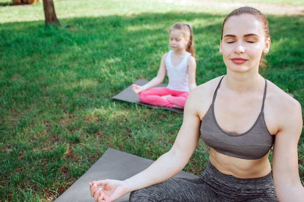 La donna e la ragazza stanno meditando. sono seduti nella posizione del loto e tengono le mani sulle ginocchia. sono concentrati e rilassati allo stesso tempo.