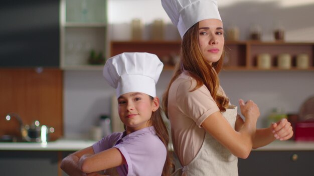 Woman and girl in cooker hats crossing hands on workplace in slow motion