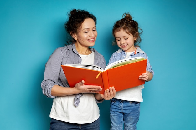 Woman and girl equally dressed hold a book in their hands