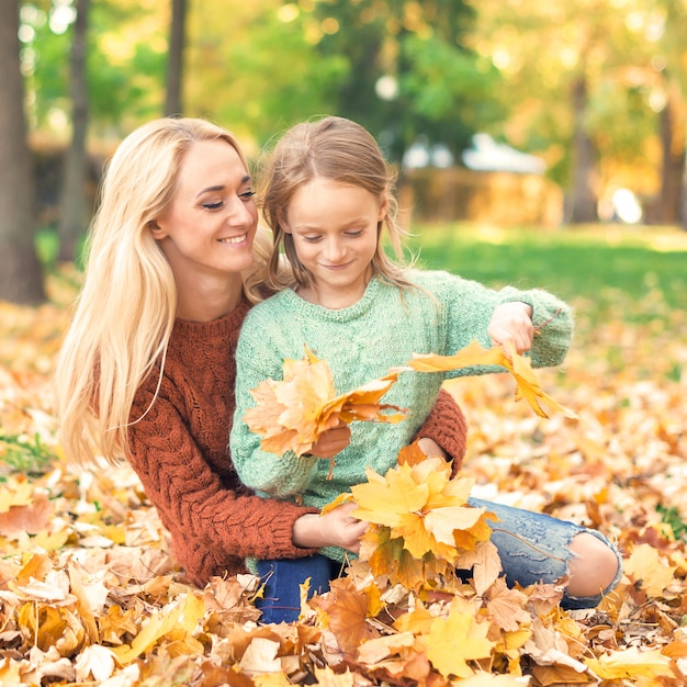 Woman and girl holding autumn yellow leaves