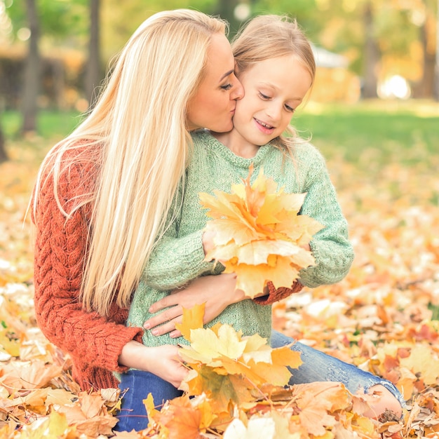 Woman and girl holding autumn yellow leaves