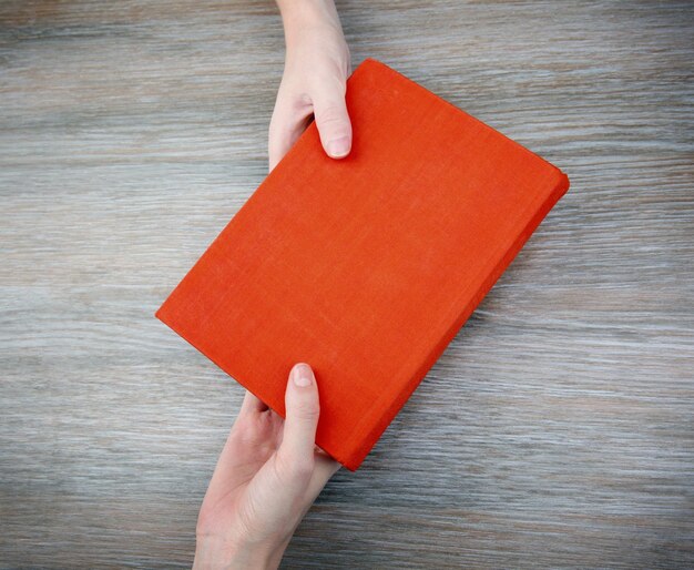 Woman giving book to woman on wooden table background