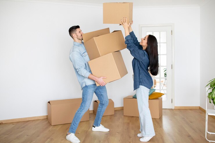 Photo 引っ越しの日に荷造りをしている間に夫に箱を渡す女性