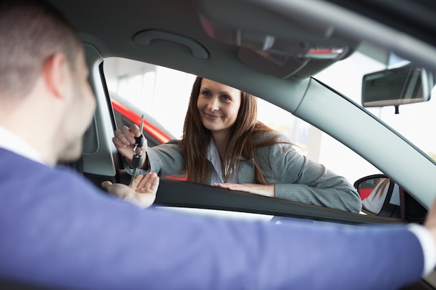 顧客に車のキーを与える女性