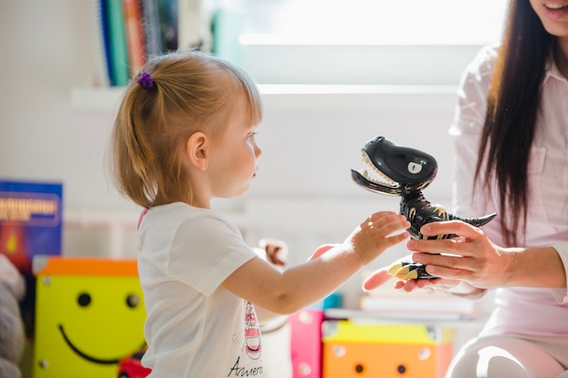 Woman giving dinosaur to girl