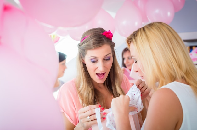 Woman giving gift to pregnant friend on baby shower