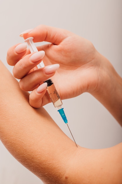 Photo woman giving an injection into a vein in her arm