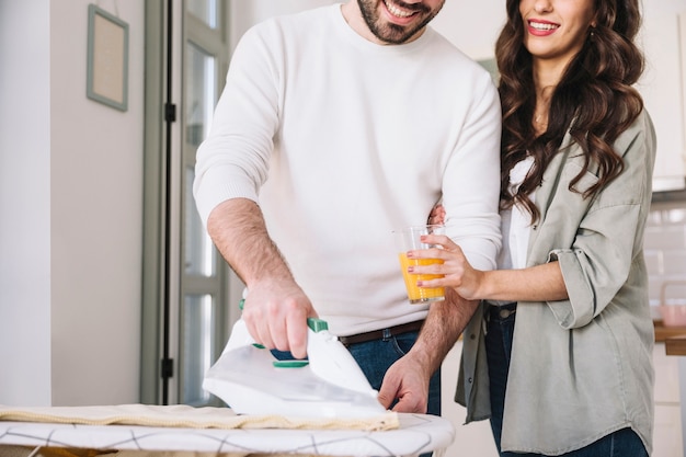 Woman giving juice to ironing man