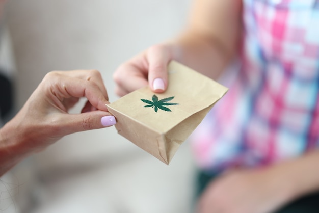 Donna che dà il sacchetto di carta del primo piano della marijuana